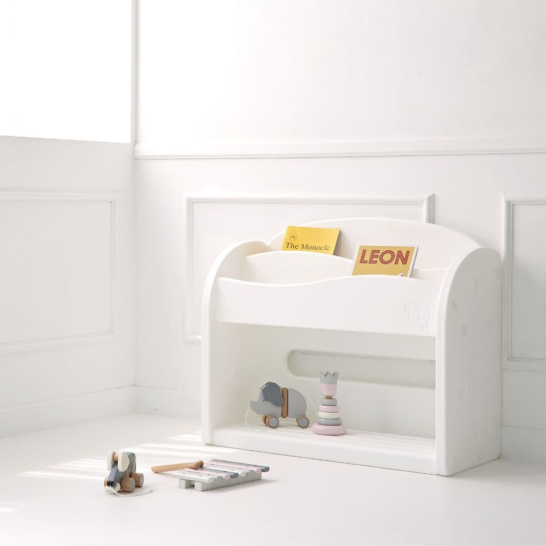 White bookshelf for kids storing children books and toys in a room with white walls.